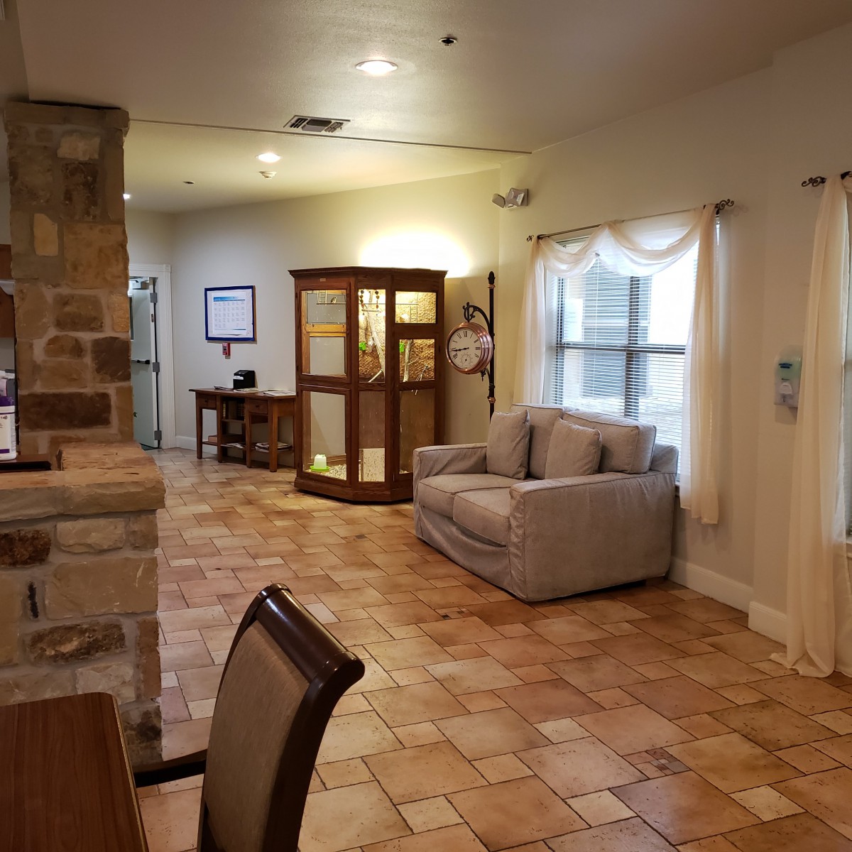 A comfortable living room with a sofa, tile flooring, and a decorative cabinet.