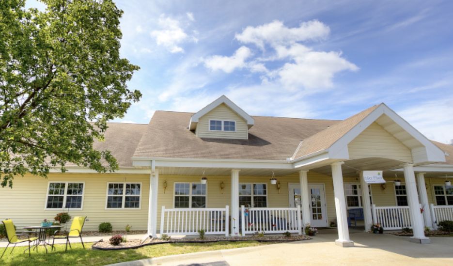 A charming residential house with a porch, set against a blue sky with scattered clouds.
