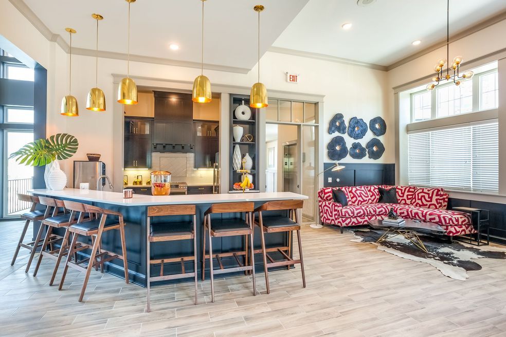 A modern open floor plan combines a stylish kitchen and a comfortable living area, featuring decorative elements and cozy seating.