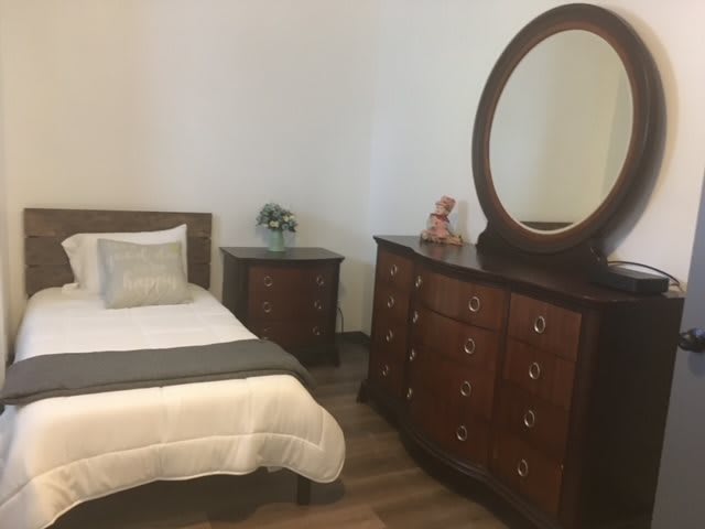 A cozy bedroom with wooden furniture and a large mirror.