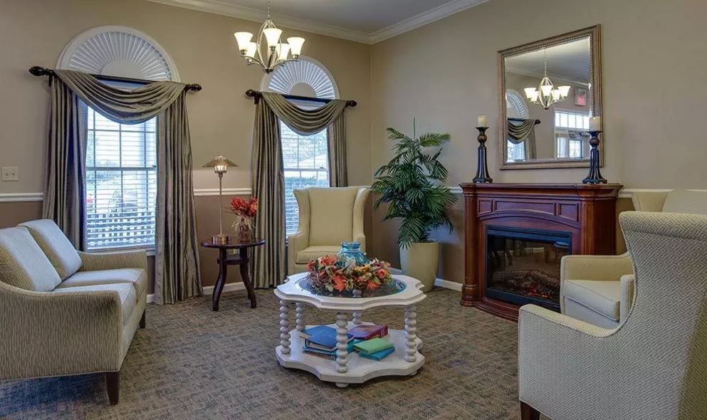 A cozy living room with elegant furnishings, featuring a fireplace and large windows.