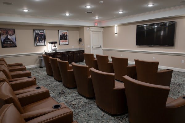 A cozy home theater room with multiple rows of comfortable seating and a large screen.