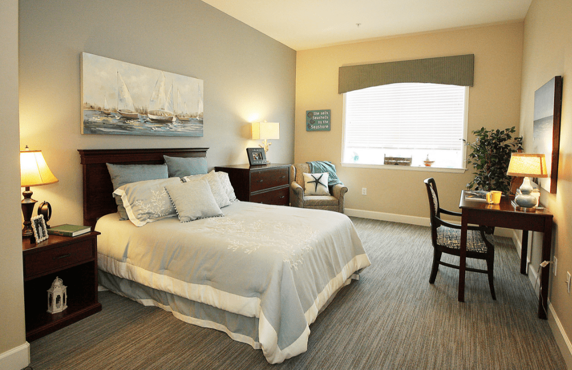 A cozy bedroom with a neatly made bed, warm lighting, and simple decor.