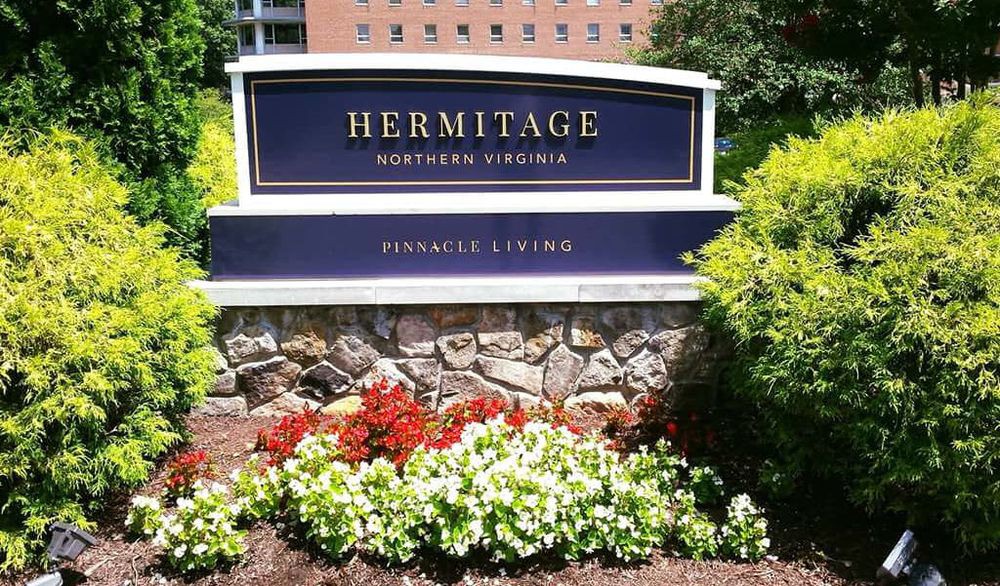 Sign for Hermitage Northern Virginia surrounded by landscaped flowers.