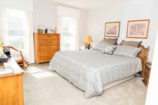 A cozy bedroom with a large bed and wooden dresser, bathed in natural light.