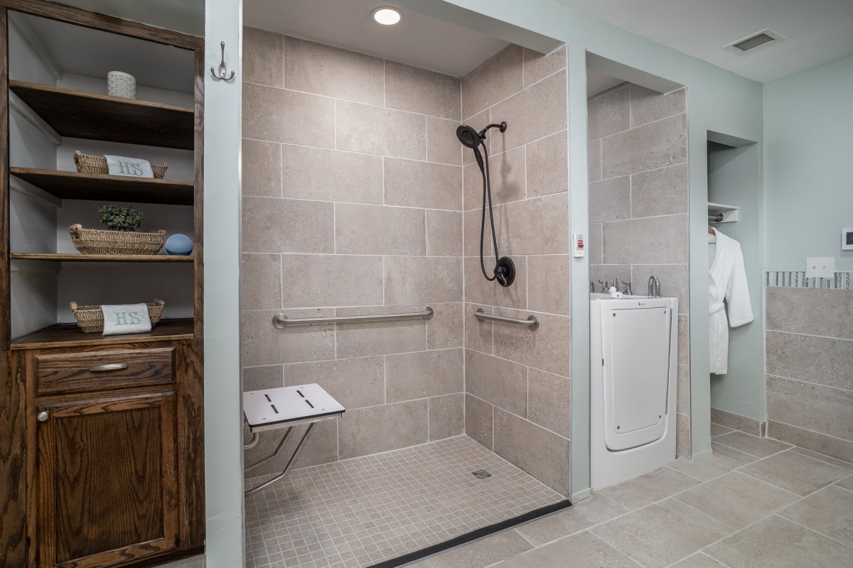 A modern, accessible walk-in shower with grab bars and a folding seat.