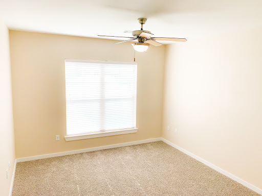 A bright and empty room featuring a ceiling fan and large window.