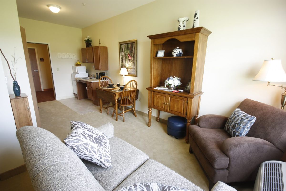 A cozy living room with a sofa, wooden cabinet, and a desk with a lamp.