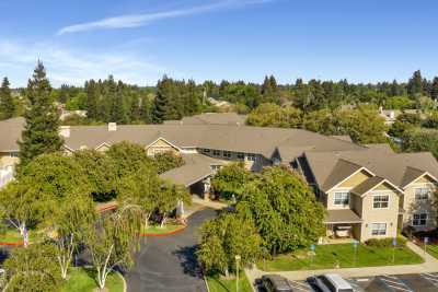 Aerial view of a building surrounded by lush greenery and a parking lot.