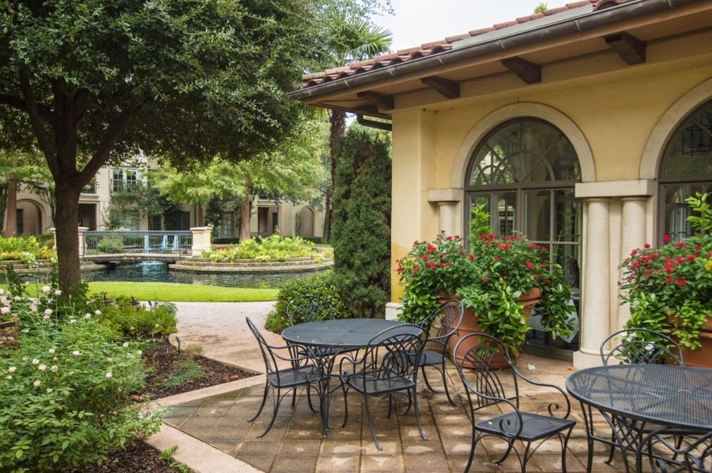 A serene patio with outdoor furniture surrounded by lush greenery and architectural features.