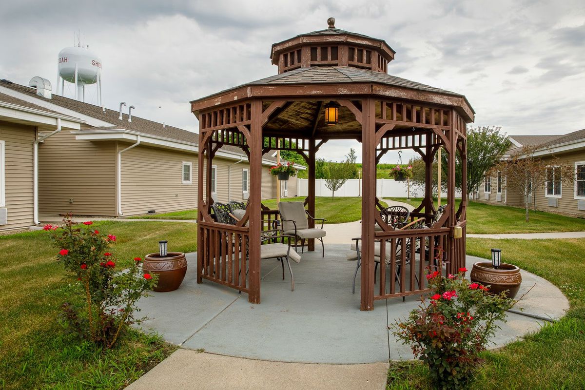A wooden gazebo with seating in a landscaped garden setting.