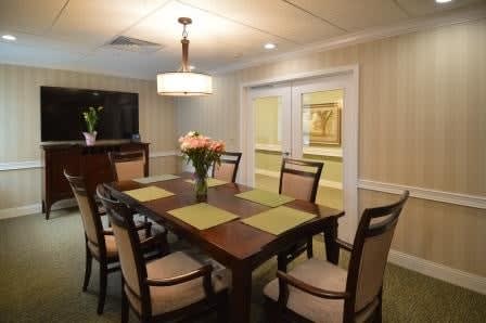 A neatly arranged dining room with a wooden table, chairs, and elegant lighting.
