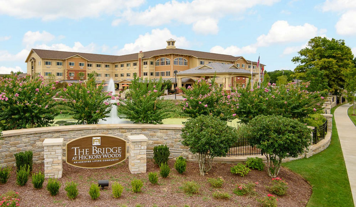 A large, elegant building with a fountain and landscaped garden in front, featuring a sign that reads 'The Bridge'.