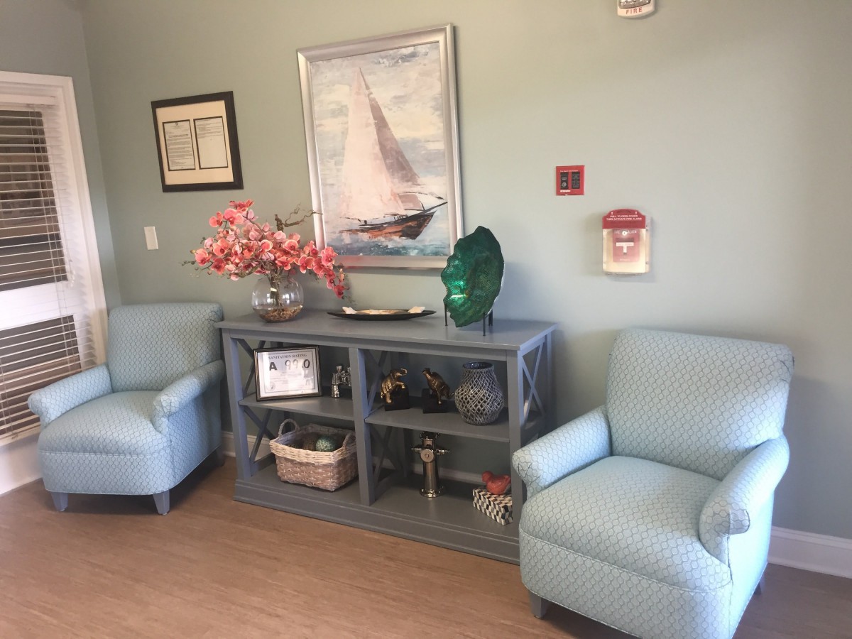 A cozy waiting room with two comfortable chairs, decorative elements, and a painting of a sailboat on the wall.