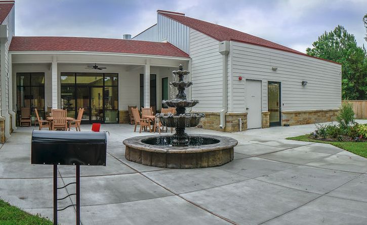 A modern building with a patio featuring a central fountain and outdoor seating.
