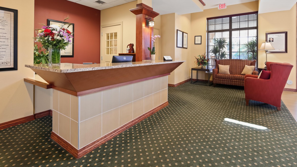 A hotel lobby with a reception desk and a waiting area.