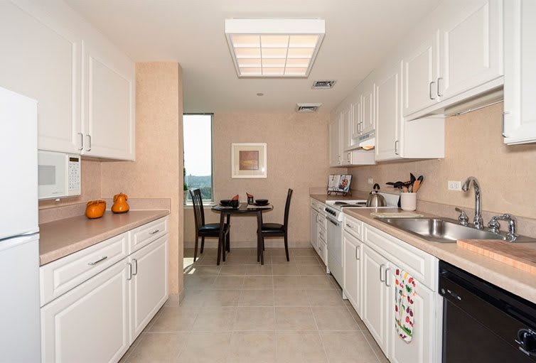 A modern, clean kitchen with white cabinets and a small dining area.
