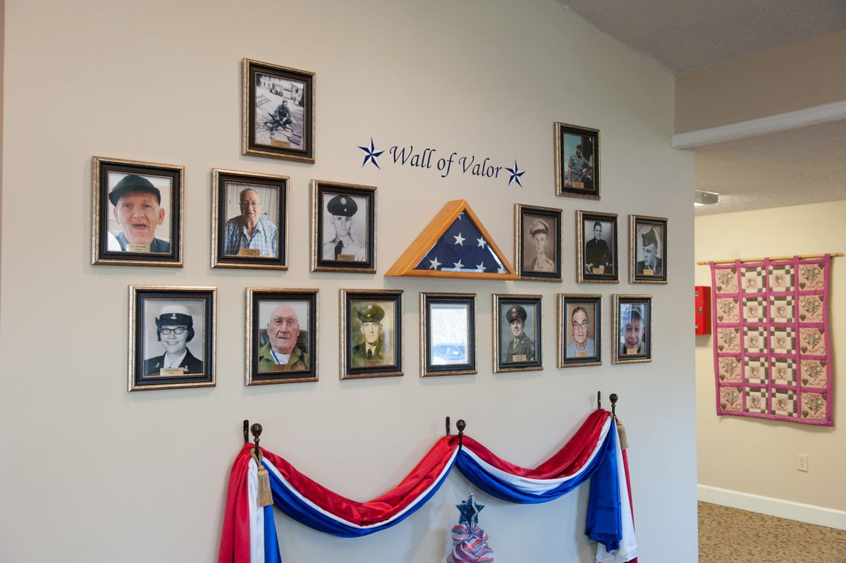 A Wall of Honor featuring framed photographs of veterans, adorned with patriotic decorations and an American flag.