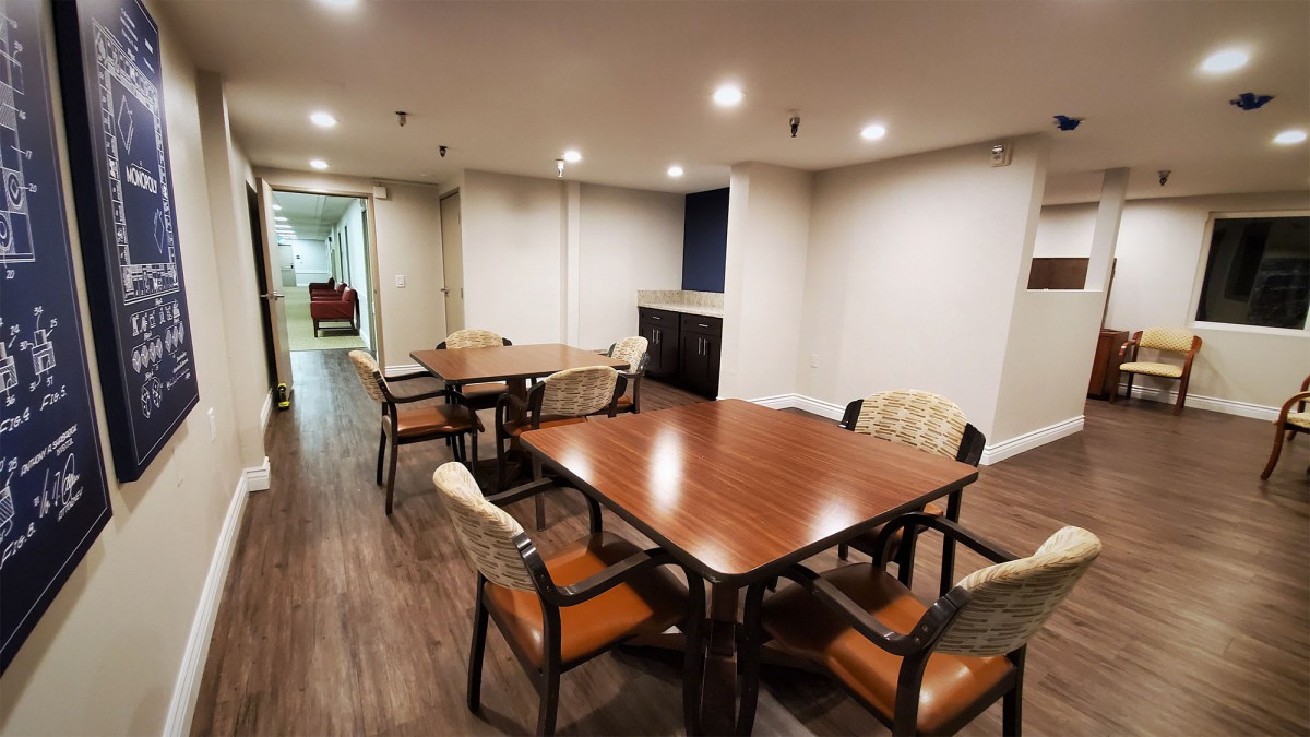 A cozy dining area with wooden tables and chairs, featuring a well-lit interior and wood flooring.