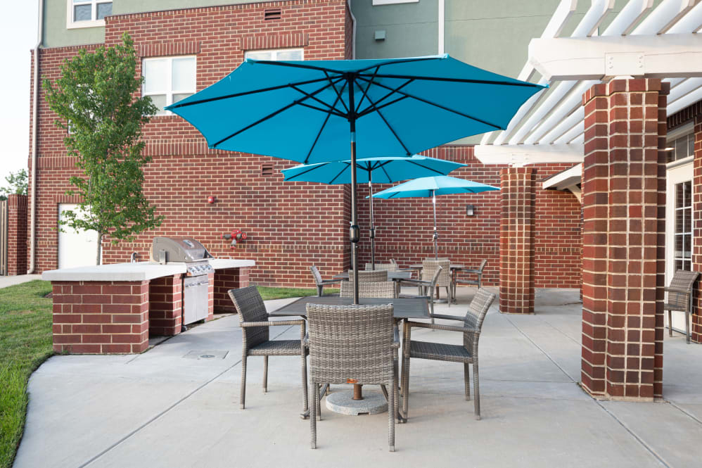 An outdoor patio area with tables and chairs under blue umbrellas.