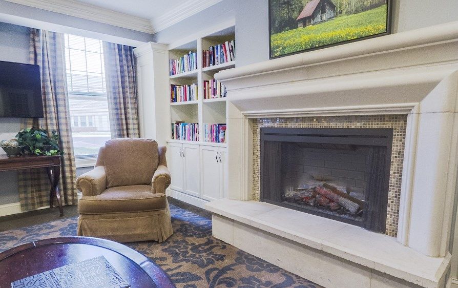 A cozy living room with a fireplace, armchair, and bookshelf.