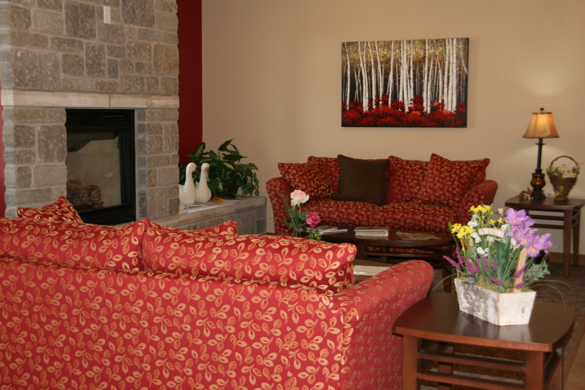 A cozy living room featuring red sofas, a stone fireplace, and wall artwork.