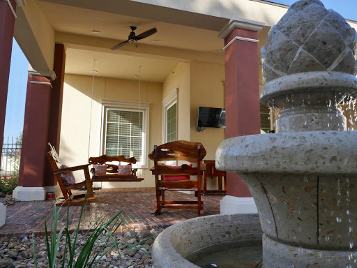 A serene outdoor patio featuring comfortable seating and a decorative fountain.