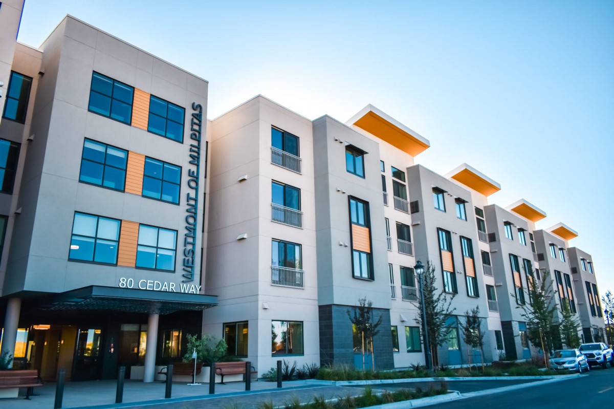 A modern apartment complex with multiple stories and large windows.