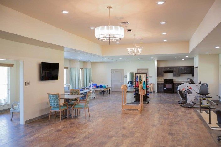 A spacious and modern living room with a chandelier, seating area, and television.