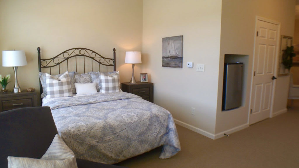 A cozy bedroom with a neatly made bed and a bedside lamp.