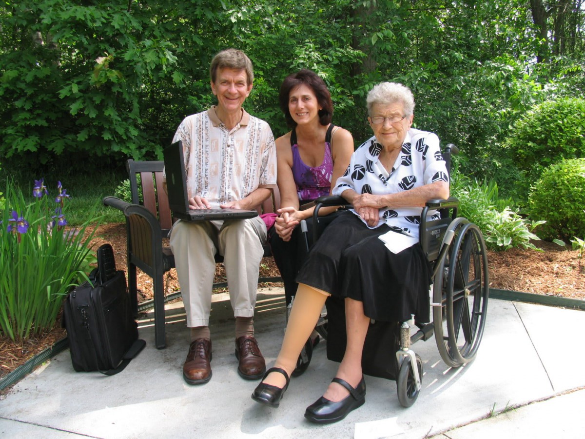 A group of three people sitting together on a park bench, enjoying a moment outdoors.
