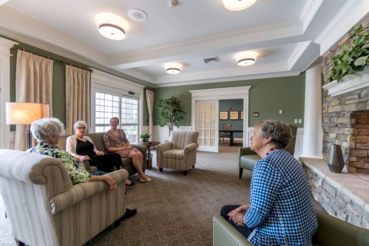 A group of seniors sitting in a living room having a conversation.