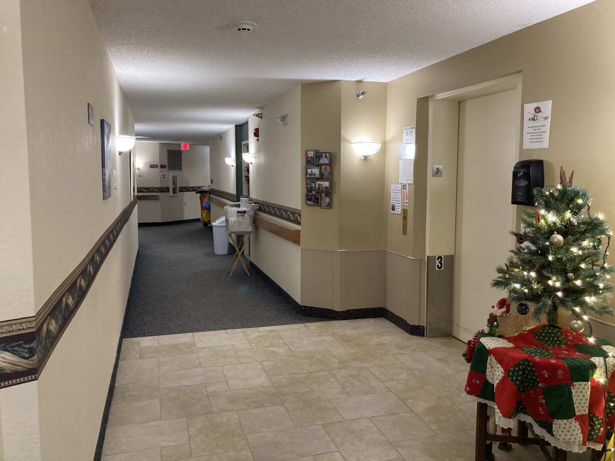 A well-lit hallway in a nursing home decorated with festive Christmas decorations.