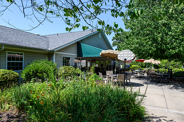 A cozy patio with outdoor seating surrounded by lush greenery on a sunny day.