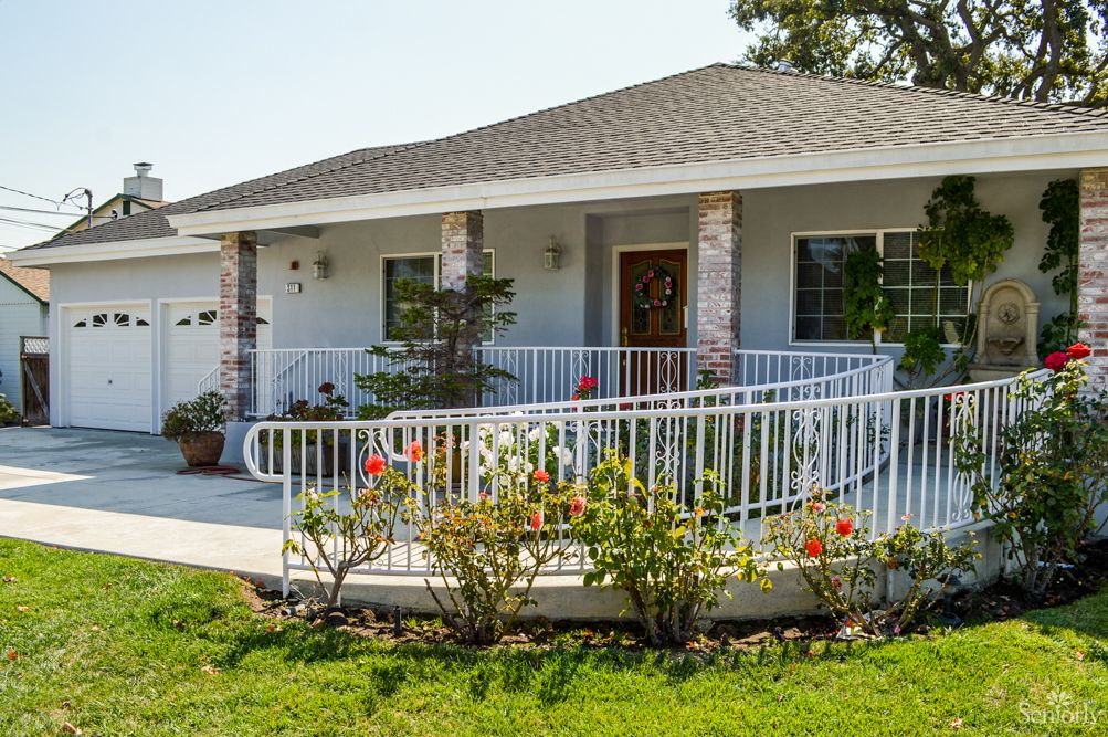 A single-story house with a ramp and porch, surrounded by a landscaped garden.