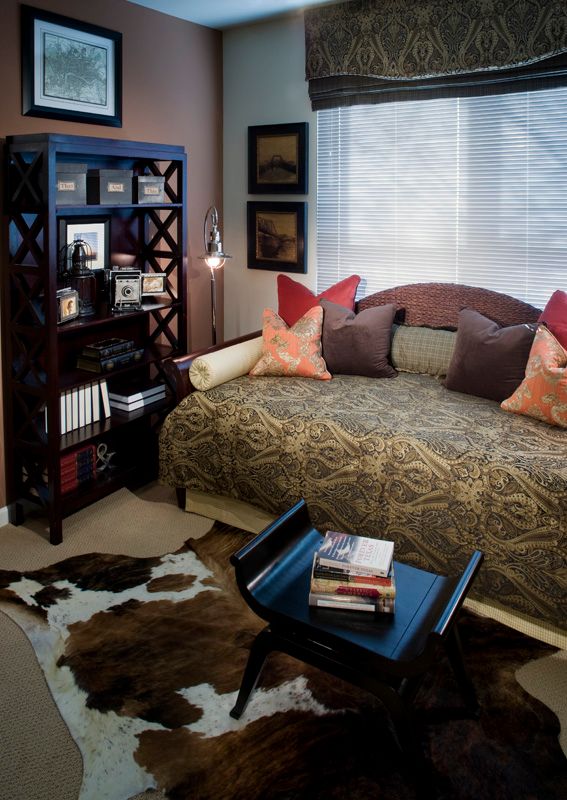 A cozy bedroom with a stylish daybed, decorative pillows, and a well-organized bookshelf.