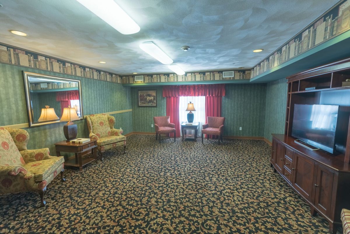 A vintage living room with patterned carpet, classic furniture, and decorative lamps.
