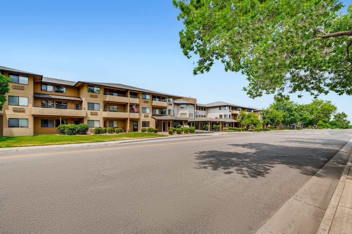 A suburban apartment building along a quiet street lined with trees.