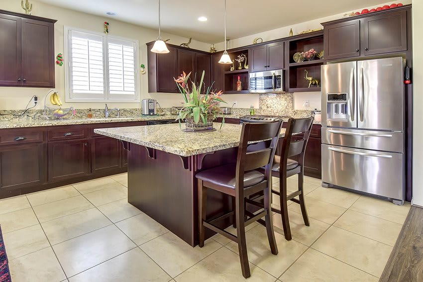 A modern kitchen with an island, granite countertops, and stainless steel appliances.