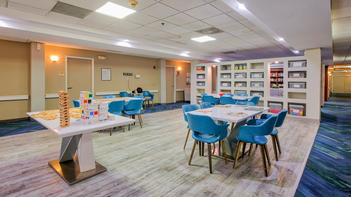 A modern library space with blue chairs, tables, and bookshelves filled with books.