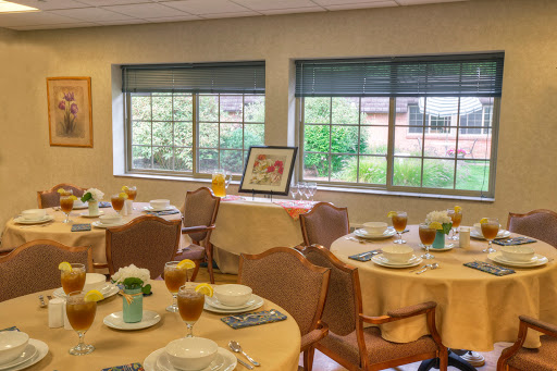 A beautifully set dining room ready for an event, featuring elegantly arranged tables and a view of the outdoors.