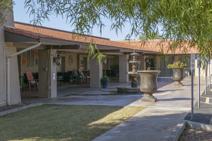 A serene courtyard featuring a fountain, surrounded by columns and lush landscaping.