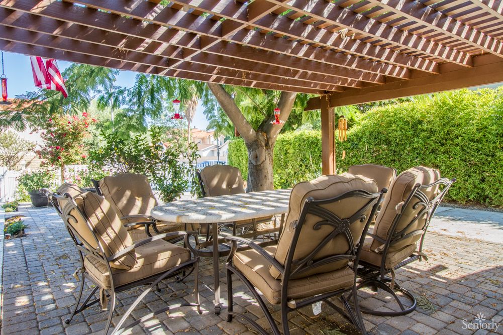 A cozy outdoor patio set under a pergola in a serene garden setting.