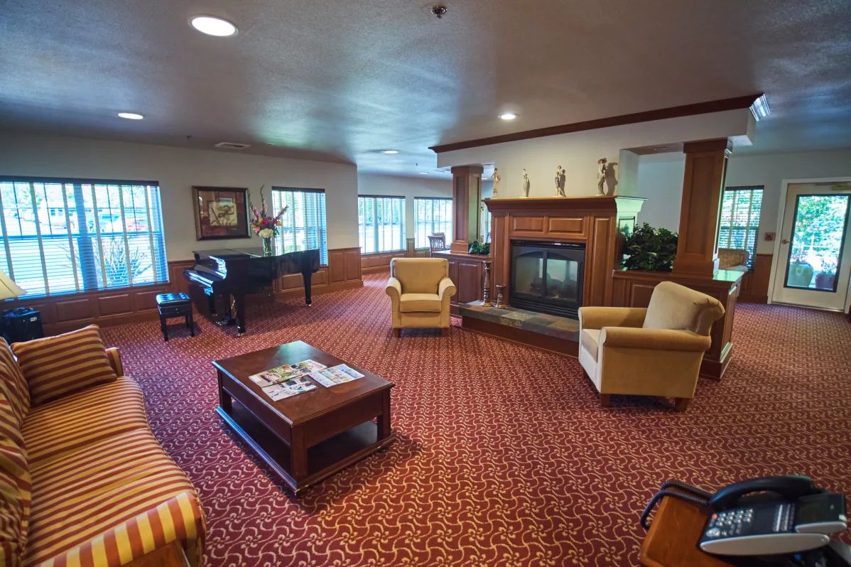 A cozy living room featuring a grand piano, comfortable seating, and a fireplace.