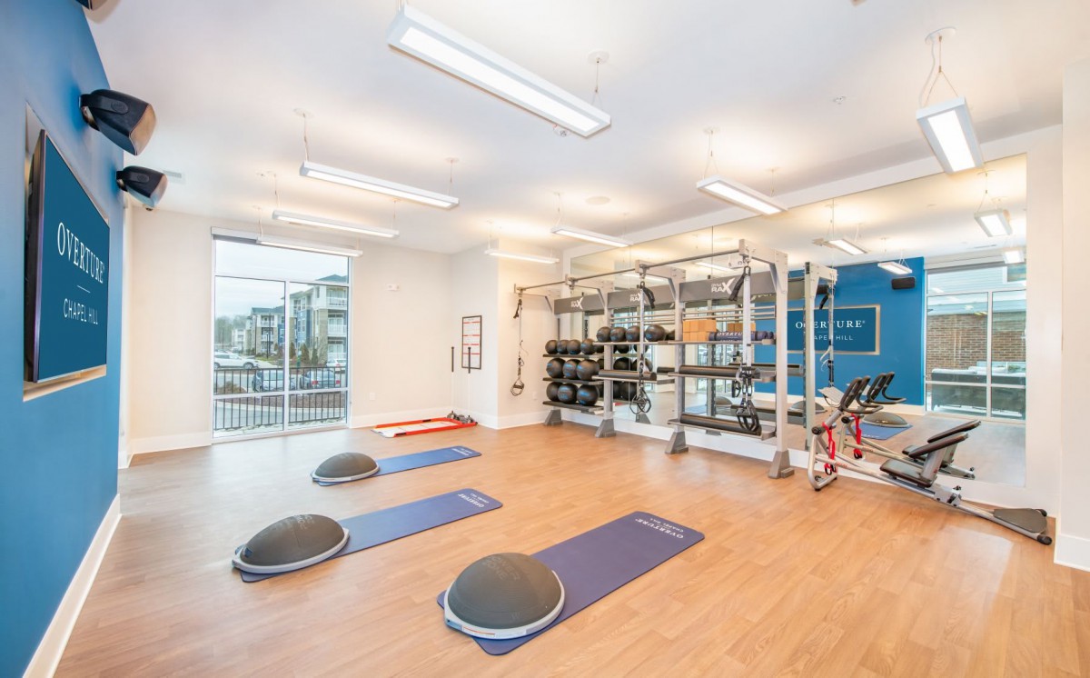 A spacious fitness center with exercise equipment and bright natural lighting.
