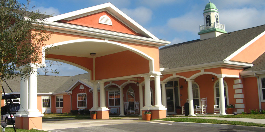 A building with a covered entrance featuring columns and a pitched roof.