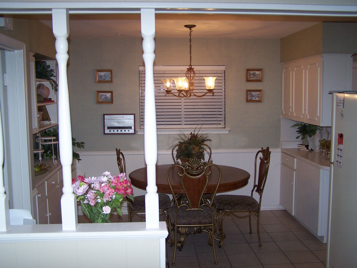 A cozy dining room with a round table, decorative plants, and a chandelier overhead.