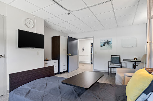 A modern hospital room featuring a bed, television, and seating area.