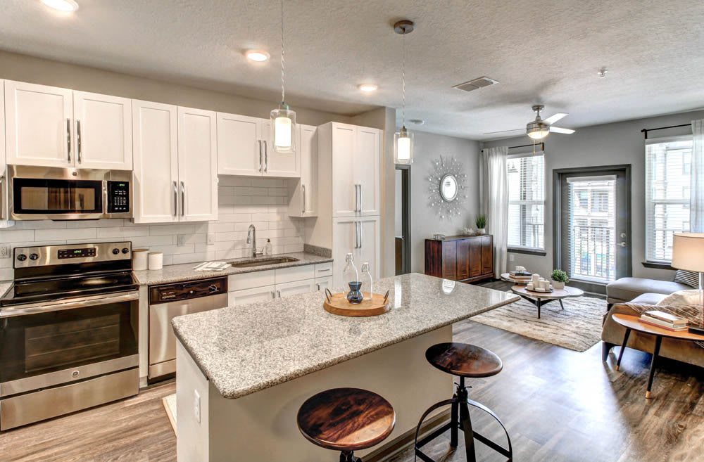 A modern open-concept kitchen with a central island and stylish pendant lighting, seamlessly connected to a cozy living area.