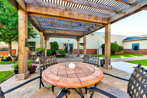 A serene outdoor patio space featuring a wooden pergola and a circular table, perfect for relaxation and gatherings.
